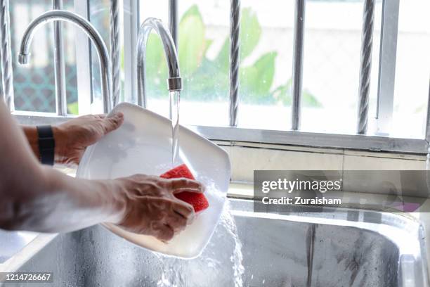 asian man washing dishes at home - laver en frottant photos et images de collection