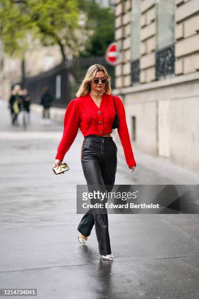 Anne-Laure Mais wears sunglasses, a necklace, a red wool jacket, black leather pants, pointy shoes, outside Alessandra Rich, during Paris Fashion...