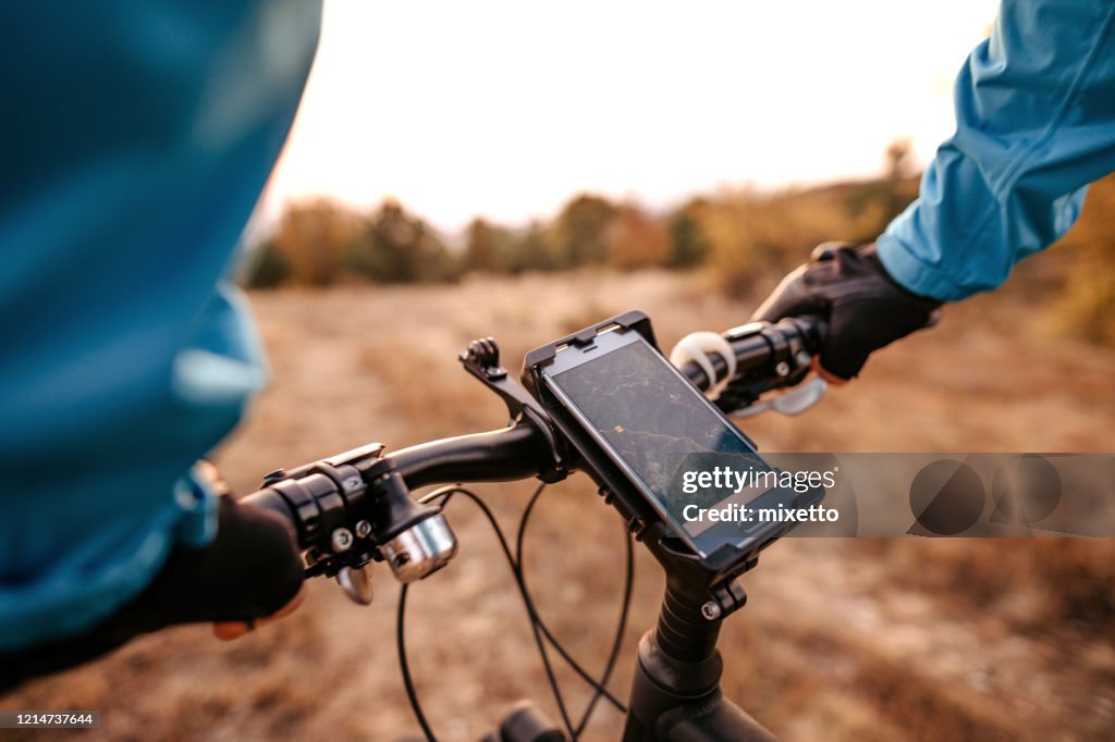 Mid adult man using navigational system while riding bicycle