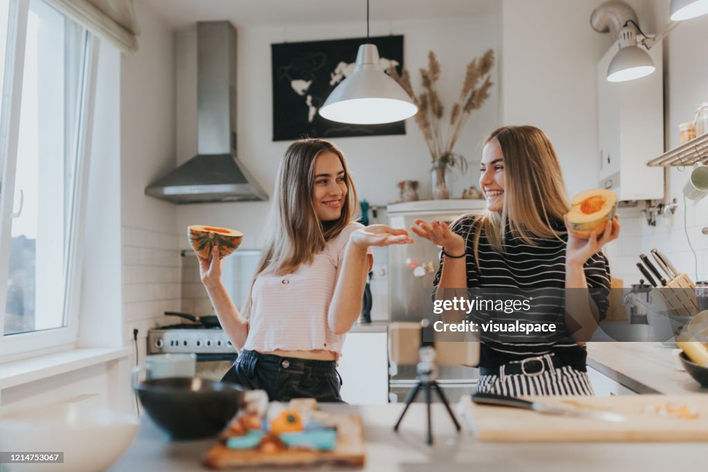 Twee tienermeisjes die een muziekvideo in de keuken met slimme telefoon filmen