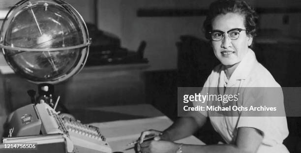 Space scientist, and mathematician Katherine Johnson poses for a portrait at her desk with an adding machine and a 'Celestial Training device' at...