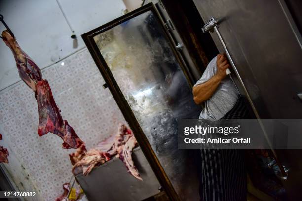 Butcher Sebastian Soria cuts beef for customers at butcher's shop La Tiernita of Villa Puyrredon area on March 25, 2020 in Buenos Aires, Argentina....