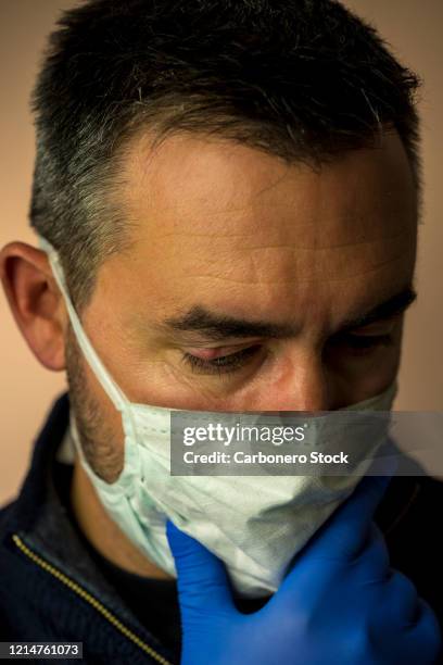 close-up of a man looking down wearing protective mask and blue gloves - hordeolum stockfoto's en -beelden