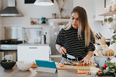 Cute female teenager cooks dinner while having a video call conversation
