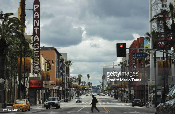 Man crosses the unusually quiet Hollywood Boulevard near the shuttered Pantages Theatre as the coronavirus pandemic continues on March 25, 2020 in...