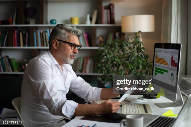 hombre usando pc de escritorio en el escritorio en la oficina en casa - investigación de mercados fotografías e imágenes de stock