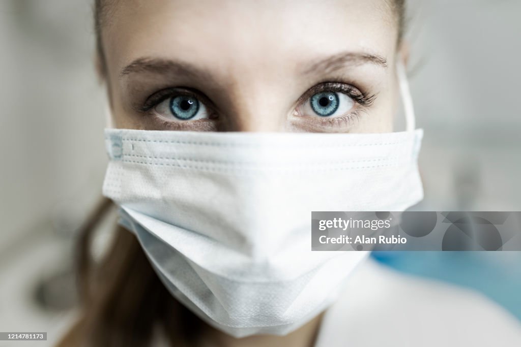 Blue-eyed nurse at her workplace wearing a protective mask.