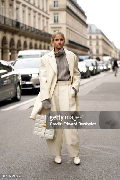 Caroline Daur wears a gray wool turtleneck pullover with long sleeves, a cream-color long oversized blazer jacket, a white quilted bag, pointy shoes,...