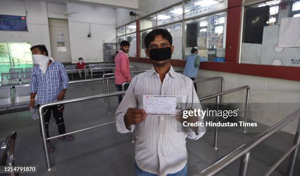 Man holds a railway ticket outside the reservation counter that was reopened following the ease in lockdown restrictions, at Karkarduma, on May 22,...