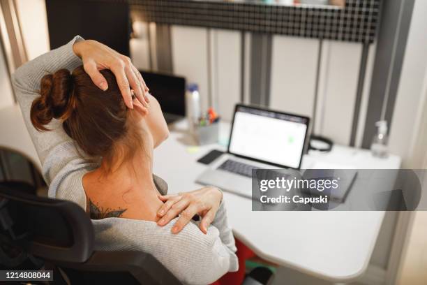 mujer estirando el cuello mientras trabaja en casa - prevention work fotografías e imágenes de stock