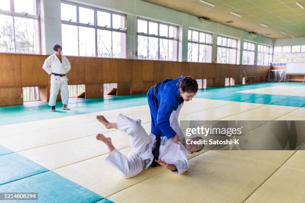 young female judo athlete attacking with “nage waza” throwing technique - jiu-jitsu stock pictures, royalty-free photos & images