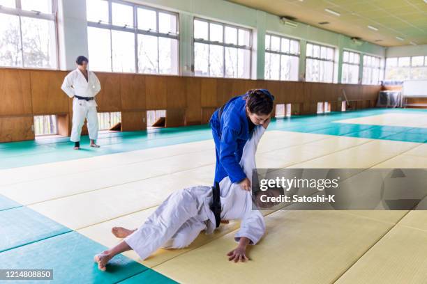 young female judo athlete attacking with “nage waza” throwing technique - judo woman stock pictures, royalty-free photos & images