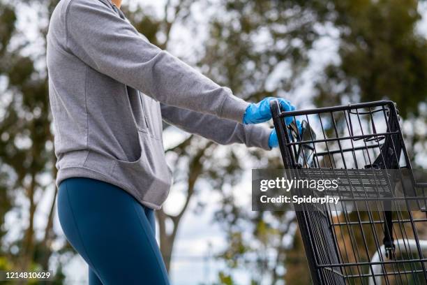 shopper wearing protective gloves pushing a grocery cart - containment boom stock pictures, royalty-free photos & images