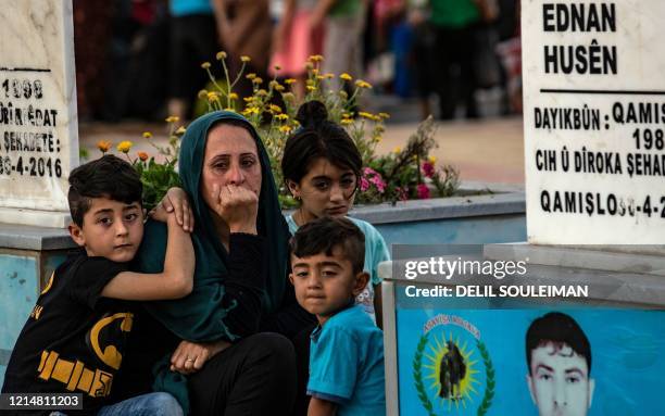 Members of the family of a slain Kurdish fighter with the Syrian Democratic Forces , visit his tomb on the eve of Eid el-Fitr, the Muslim holiday...