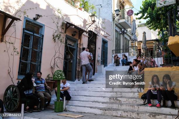 Tourists and locals mill about outside of a cafe opened for take away business in the Plaka district on May 23, 2020 in Athens, Greece. After months...