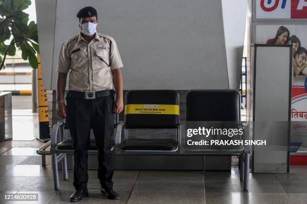 Guard stands in front of seats marked with a social distancing message at the Indira Gandhi International airport after the goverment eased a...