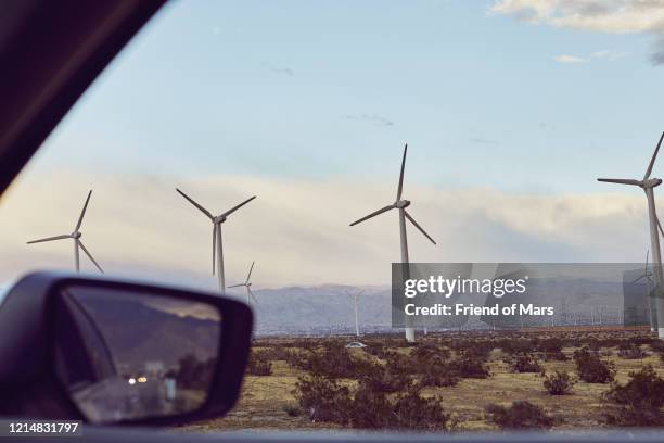 renewable and sustainable wind and solar power plant with dramatic sky taken from car window - wind turbine california stock pictures, royalty-free photos & images