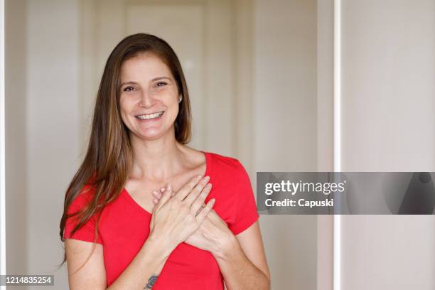 smiling woman doing social distance greeting - hands on chest stock pictures, royalty-free photos & images