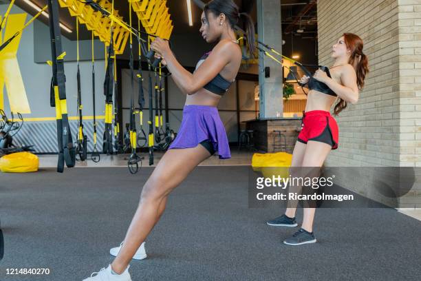 latin woman exercises her arms with the help of large ropes in the gym - entrenar stock pictures, royalty-free photos & images