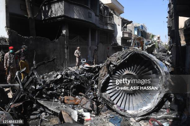 Security personnel stand beside the wreckage of a plane at the site after a Pakistan International Airlines aircraft crashed in a residential area...