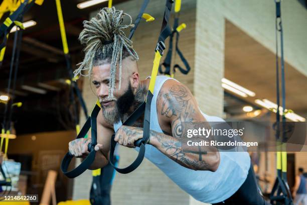 latino mens oefent zijn wapens met behulp van grote kabels in de gymnastiek uit - entrenar stockfoto's en -beelden