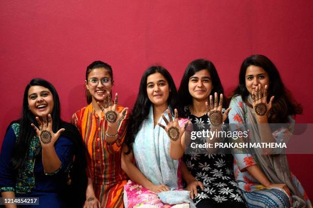 Women pose for pictures after applying hennas on their hands during 'Chand Raat' or 'Night of the Moon' in Kathmandu on May 24 on the eve of Eid...