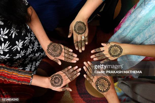 Women pose for pictures after applying hennas on the hand during 'Chand Raat' or 'Night of the Moon' in Kathmandu on May 24 on the eve of Eid al-Fitr...
