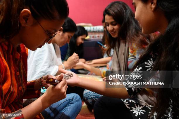 Women applies henna on their hands during 'Chand Raat' or 'Night of the Moon' in Kathmandu on May 24 on the eve of Eid al-Fitr festival. - Muslims...