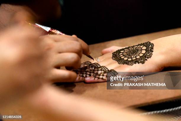 Women applies henna on their hands during 'Chand Raat' or 'Night of the Moon' in Kathmandu on May 24 on the eve of Eid al-Fitr festival. - Muslims...