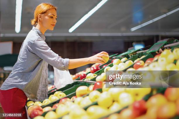 una joven comprando manzanas en el supermercado. - sac shopping fotografías e imágenes de stock