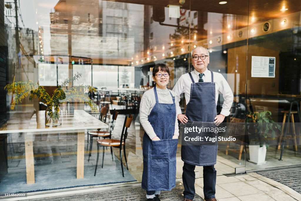 Senior couple cafe owners working happily in cafe together