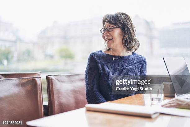 senior entrepreneurs have a work meeting in a cafe - business woman looking over shoulder stock pictures, royalty-free photos & images