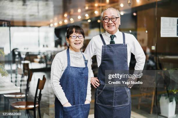 senior couple cafe owners working happily in cafe together - ready fokus blick in die kamera stock-fotos und bilder