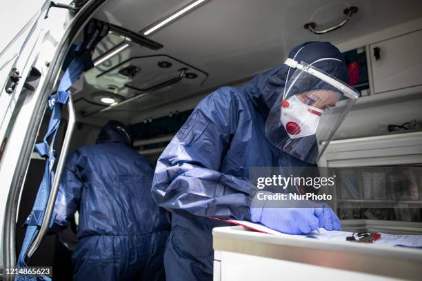Medical worker wearing protective suit, verifying patient's medical files in an ambulance in Lublin, Poland, on May 23, 2020.