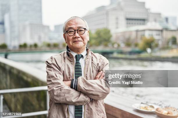 portrait of senior man on cafe terrace - old asian man stockfoto's en -beelden