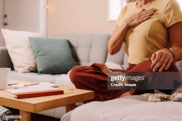 mujer en interiores relajante meditando y haciendo ejercicios de respiración - respirar fotografías e imágenes de stock