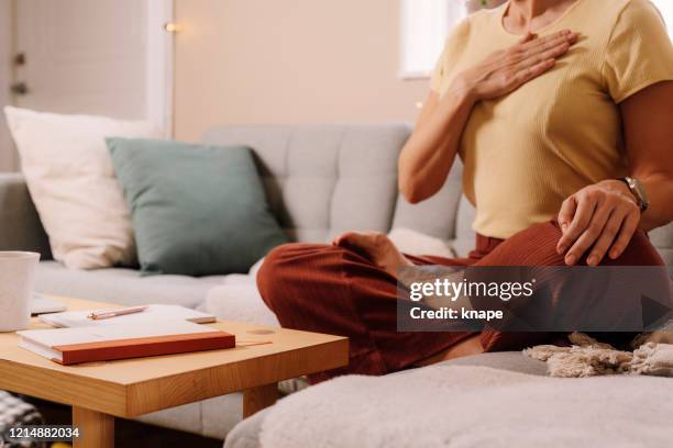 woman indoors relaxing meditating and doing breathing exercises - breathe imagens e fotografias de stock