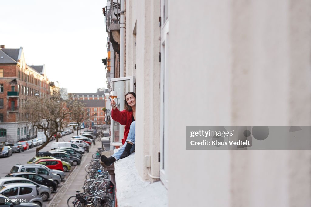 Portrait happy young woman with wine in apartment window