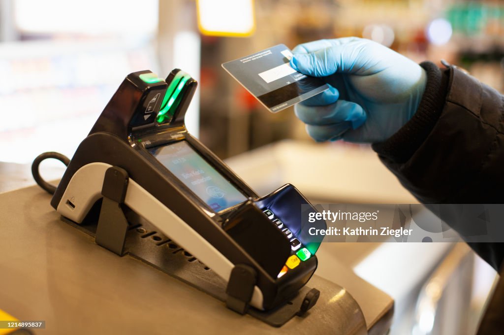 Man making a cashless payment at supermarket, wearing protective gloves