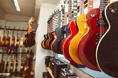 Close up of electric guitars in a row in huge instrument shop, music instrumental concept