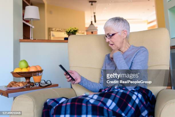staying connected and up to date during her retirement - staying indoors stock pictures, royalty-free photos & images