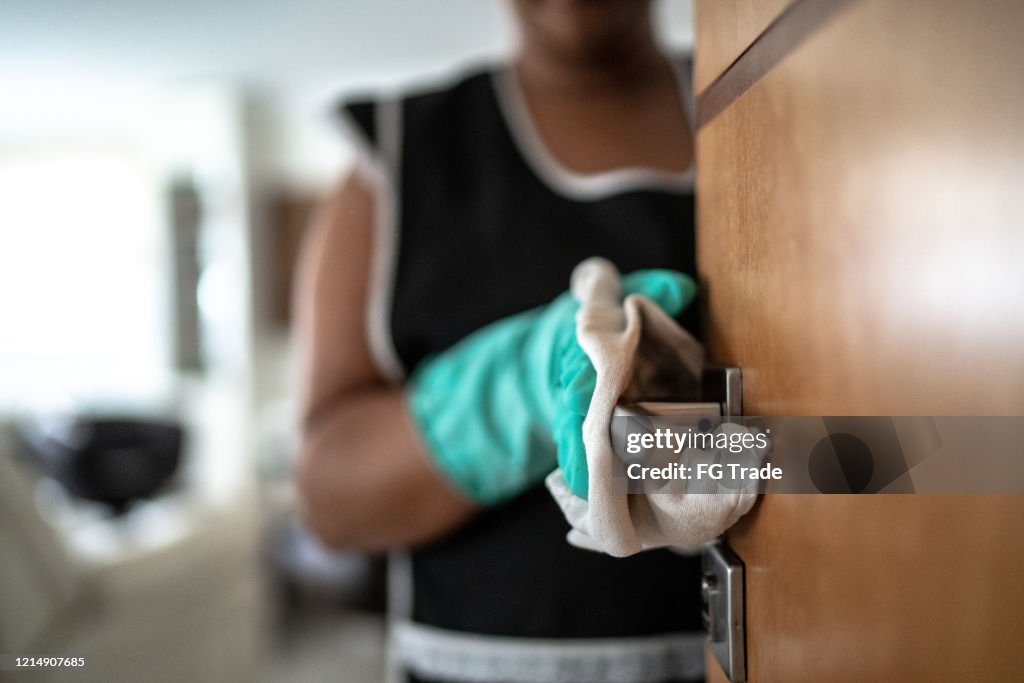 Hands with glove wiping doorknob