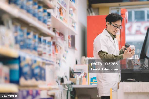 an asian chinese male pharmacist scanning pharmacy product for the pricing for his customer at the store - prescription drug costs stock pictures, royalty-free photos & images