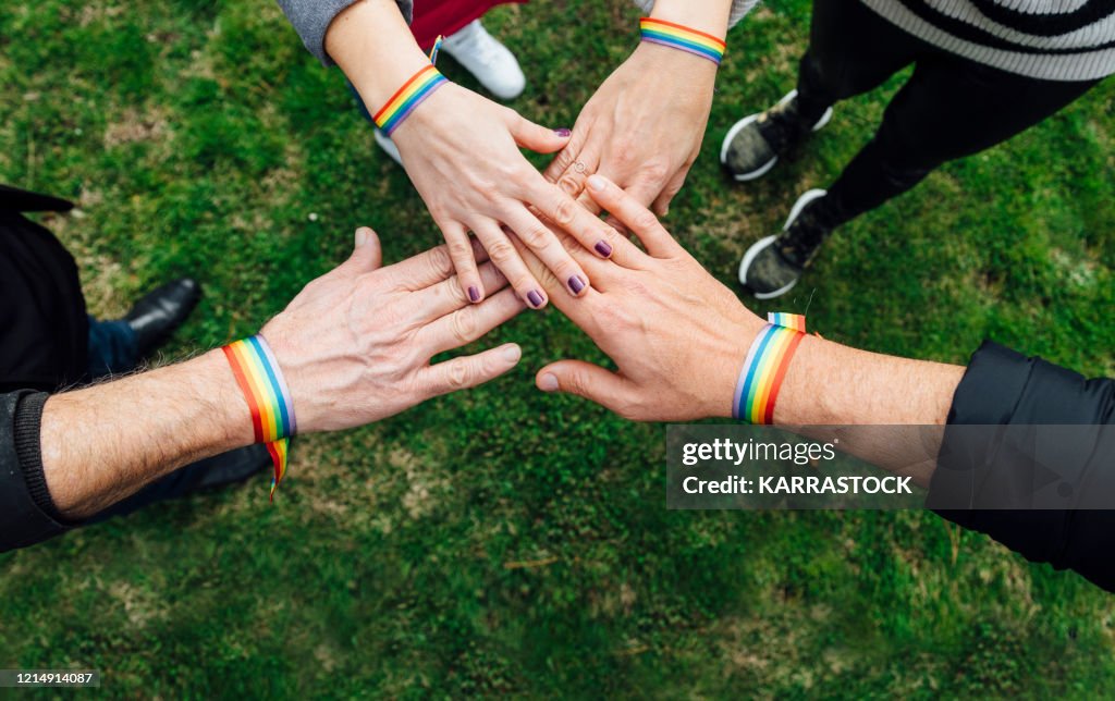 Unity hands of diverse people with multicolored bracelet