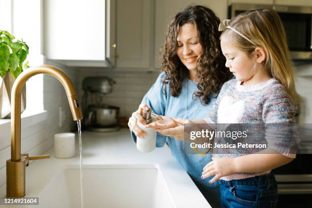 mother and daughter washing hands in kitchen sink - soap dispenser stock pictures, royalty-free photos & images