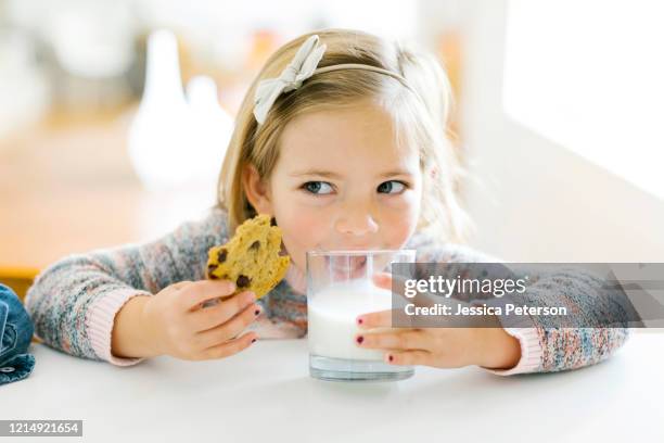 girl eating milk and cookies - eating cookies foto e immagini stock