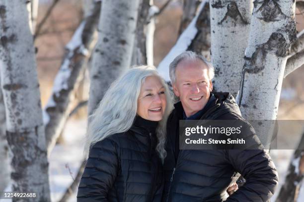 smiling senior couple by tree - active seniors winter stock pictures, royalty-free photos & images