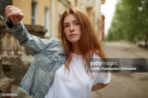 teenage girl putting on denim jacket - redhead girl - fotografias e filmes do acervo