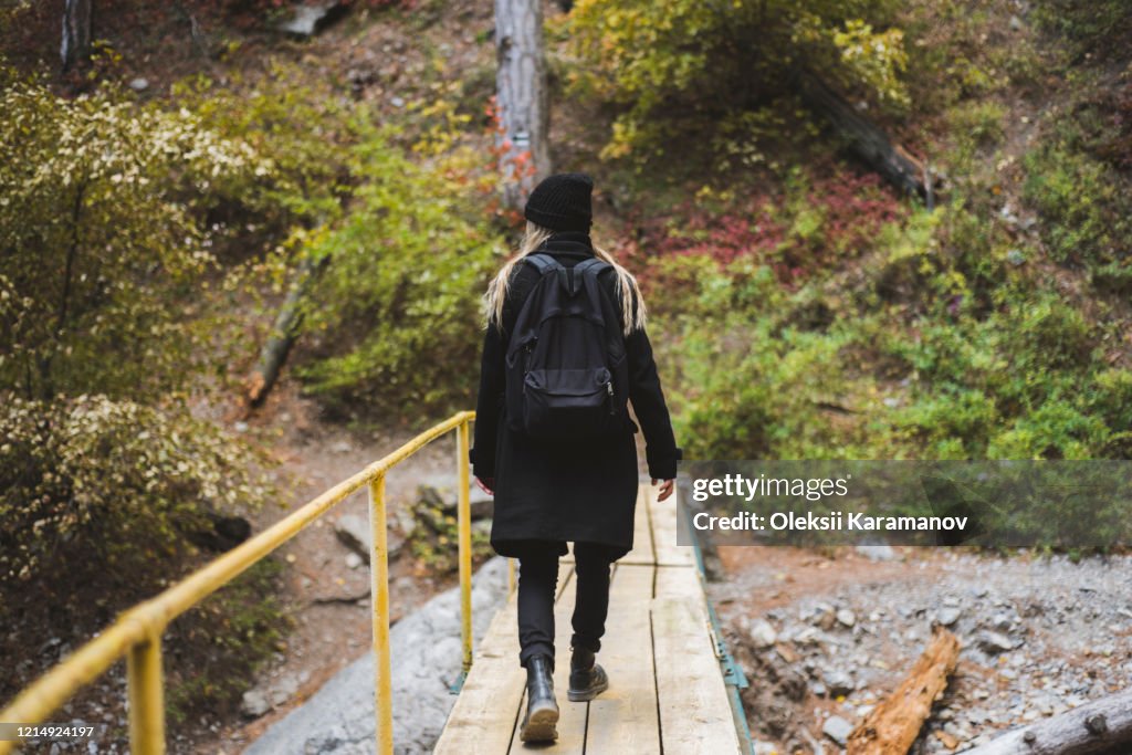 Young woman walking across bridge in forest