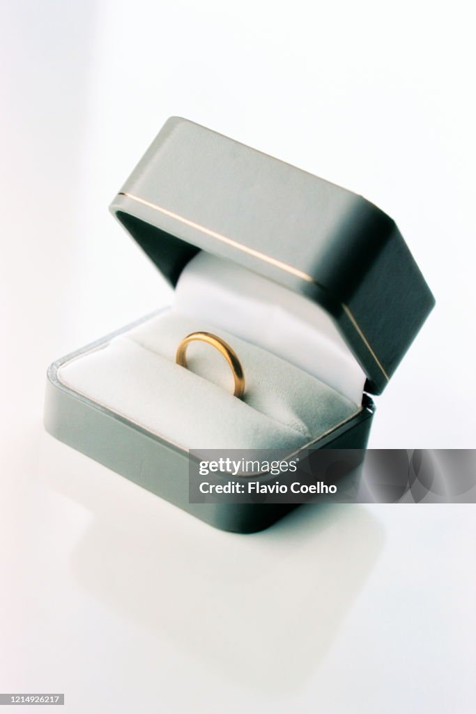 Single wedding ring in a box on white background